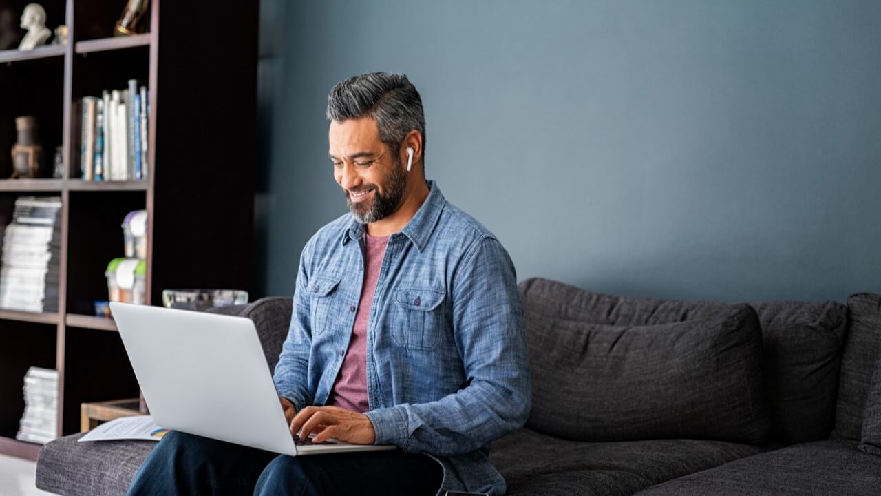 Remote worker happily using his laptop, enabled with zero trust security - with zero trust network access (ZTNA).