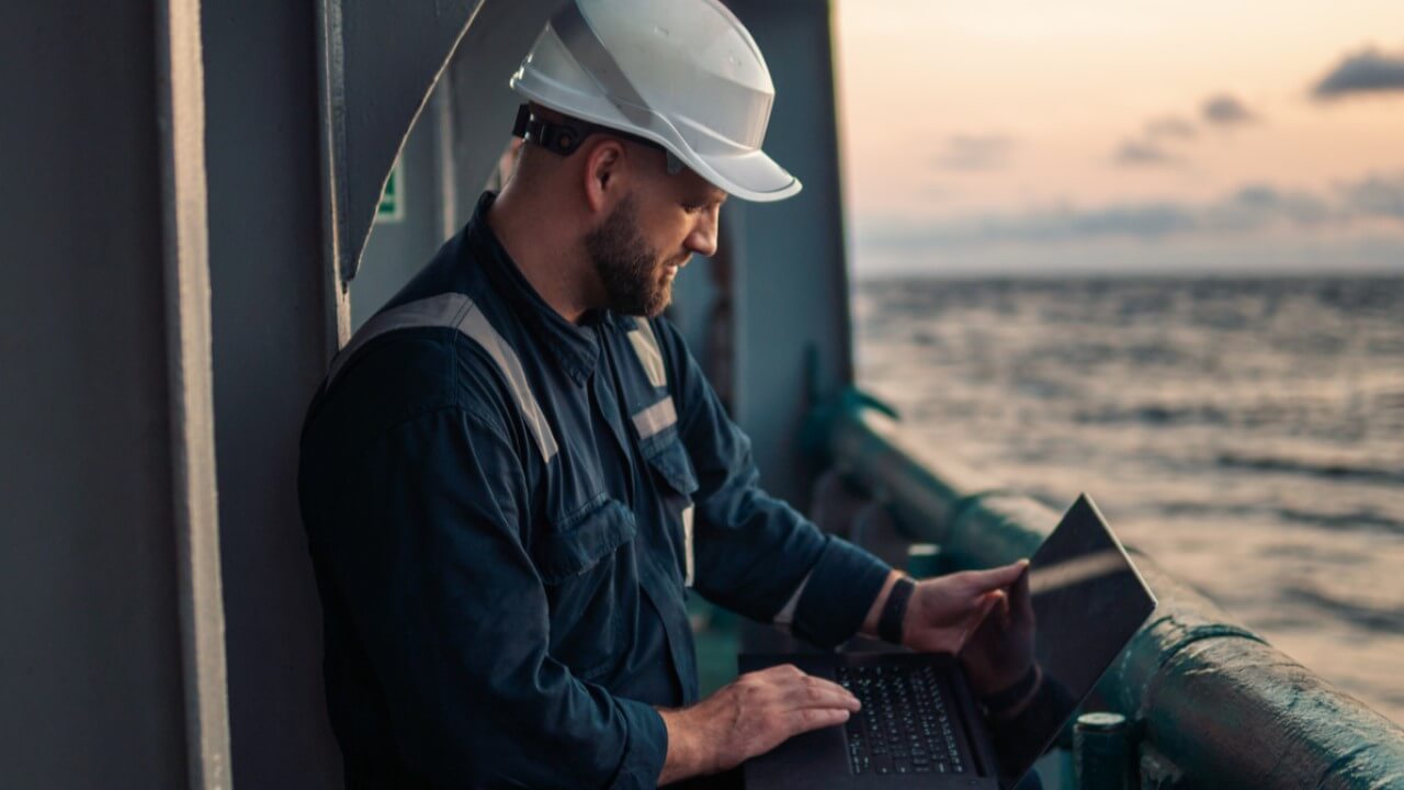 Man using laptop on ship with cyber security solutions installed.